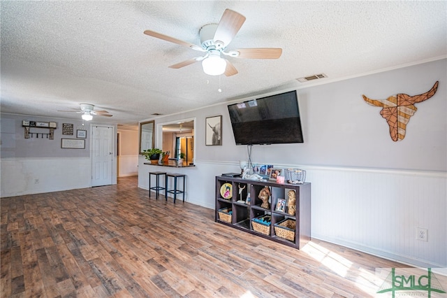 living room with ceiling fan, hardwood / wood-style floors, and a textured ceiling