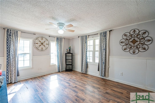 empty room with dark hardwood / wood-style flooring, ceiling fan, crown molding, and a textured ceiling