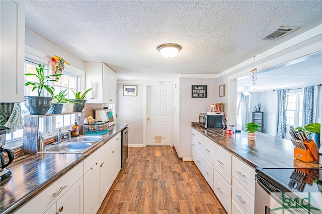 kitchen featuring appliances with stainless steel finishes, sink, white cabinets, a healthy amount of sunlight, and light hardwood / wood-style flooring