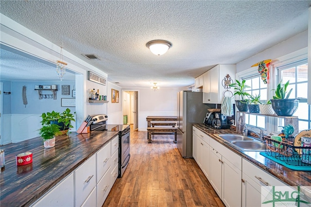 kitchen featuring sink, stainless steel appliances, a textured ceiling, white cabinets, and dark hardwood / wood-style flooring