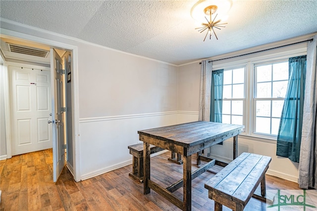 dining room featuring crown molding, wood-type flooring, and a textured ceiling