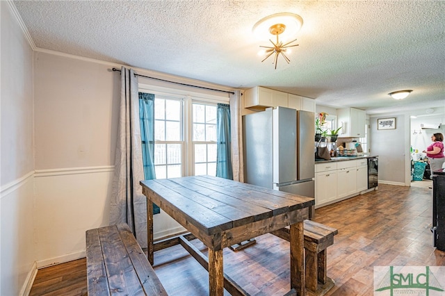 dining room featuring hardwood / wood-style floors, beverage cooler, and a textured ceiling