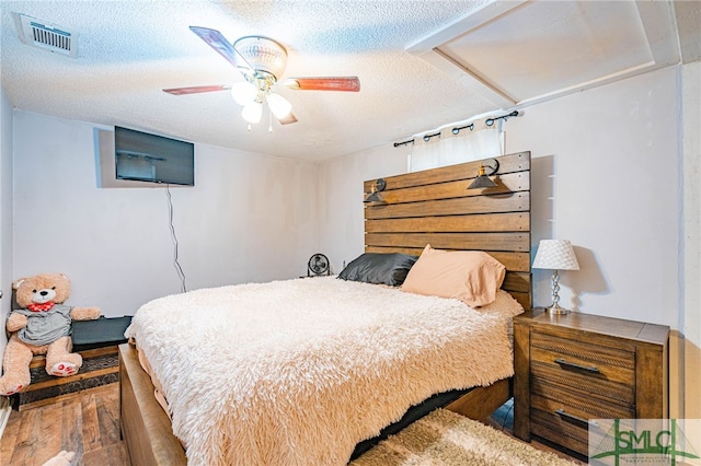 bedroom with hardwood / wood-style flooring, ceiling fan, and a textured ceiling