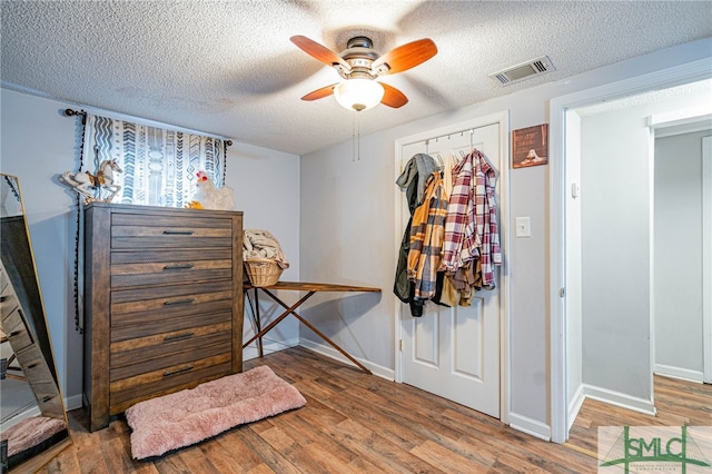 bedroom featuring ceiling fan, wood-type flooring, a closet, and a textured ceiling