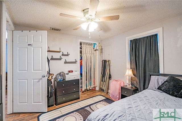 bedroom featuring ceiling fan, a closet, a textured ceiling, and light wood-type flooring