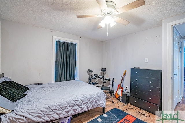 bedroom featuring hardwood / wood-style flooring, ceiling fan, and a textured ceiling