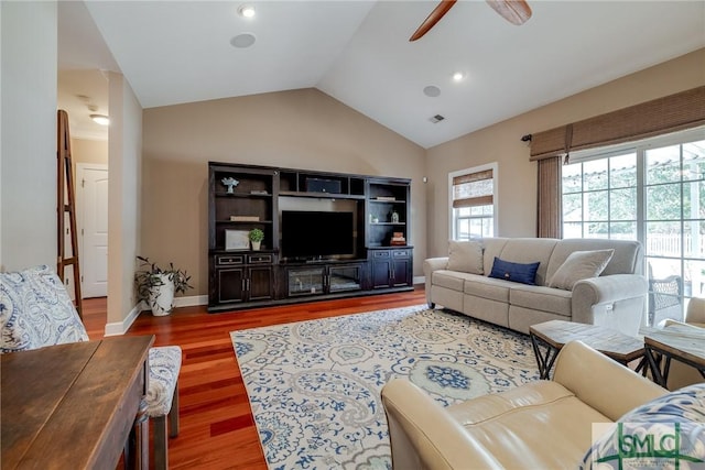 living area with lofted ceiling, wood finished floors, visible vents, a ceiling fan, and baseboards