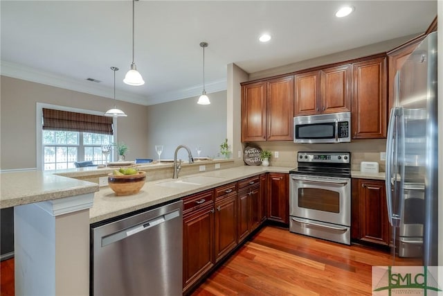 kitchen featuring hanging light fixtures, appliances with stainless steel finishes, sink, and kitchen peninsula