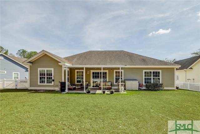 back of property with a shingled roof, a lawn, a patio area, and fence