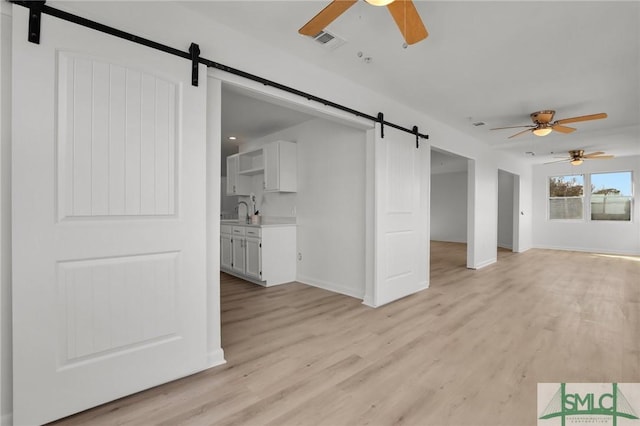 46 Captains Vw, Tybee Island, GA 31328 - unfurnished living room featuring a barn door, ceiling fan, and light wood-style flooring