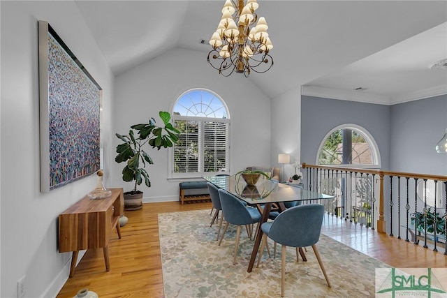 dining room with an inviting chandelier, hardwood / wood-style flooring, a wealth of natural light, and vaulted ceiling