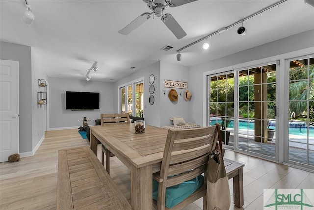 dining room with ceiling fan, rail lighting, and light hardwood / wood-style flooring