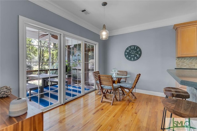 dining space with ornamental molding and light hardwood / wood-style floors