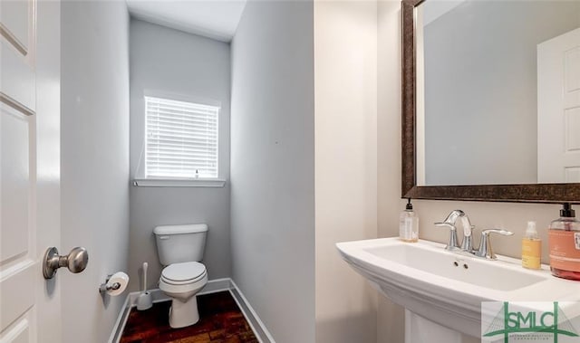 bathroom featuring toilet, sink, and hardwood / wood-style floors