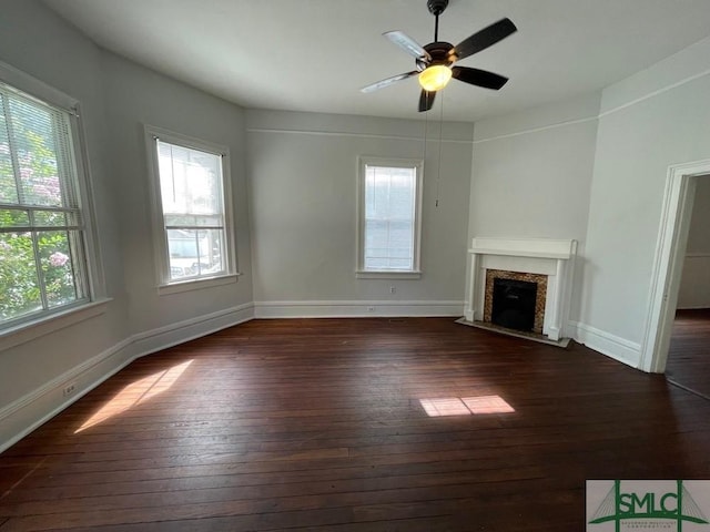 unfurnished living room featuring a high end fireplace, dark wood-type flooring, and ceiling fan