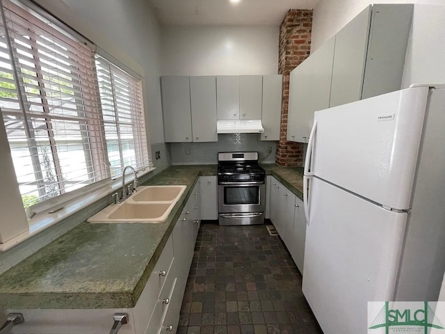 kitchen with sink, stainless steel gas range, white cabinetry, decorative backsplash, and white fridge