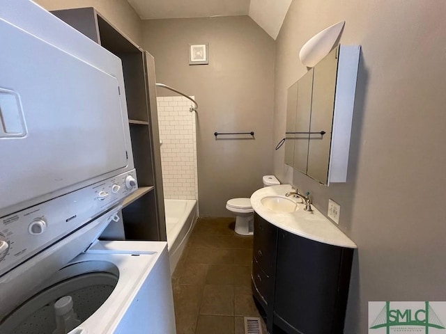 full bathroom with bathing tub / shower combination, stacked washer and clothes dryer, vanity, tile patterned floors, and toilet