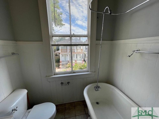 bathroom featuring tile patterned flooring, a tub, and toilet