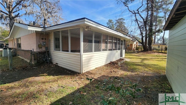 view of side of property with a sunroom and a lawn