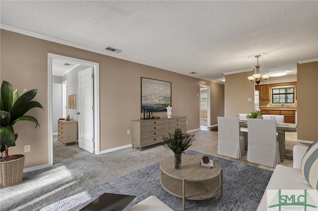 living room featuring ornamental molding, carpet, a textured ceiling, and a chandelier