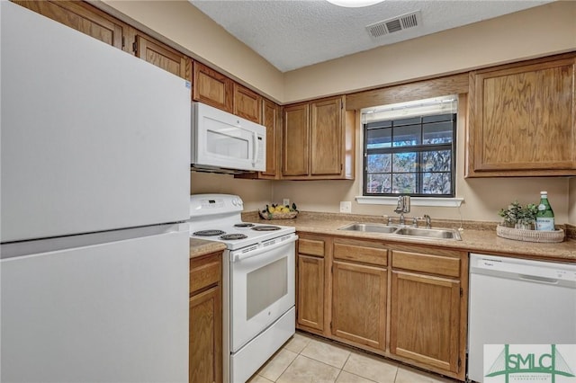 kitchen with sink, white appliances, a textured ceiling, and light tile patterned flooring