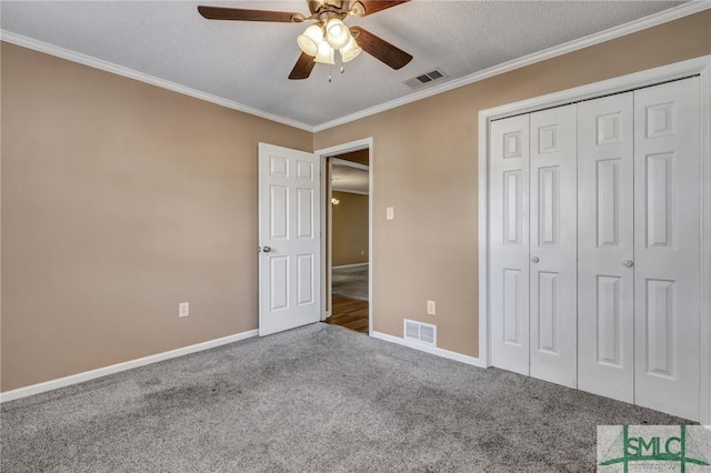 unfurnished bedroom with ceiling fan, carpet floors, ornamental molding, a textured ceiling, and a closet