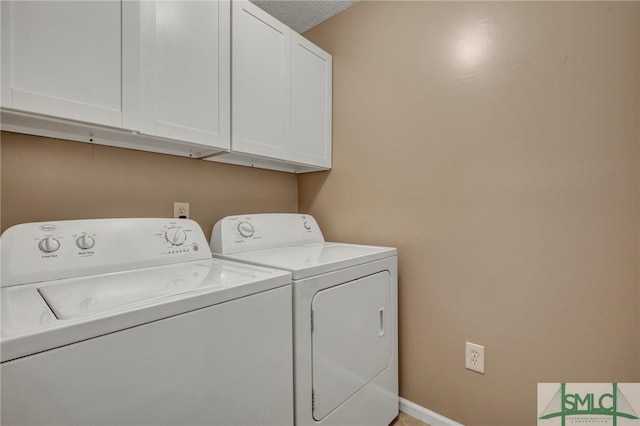 clothes washing area with cabinets and washing machine and clothes dryer