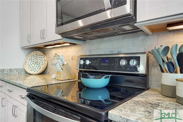 kitchen featuring light stone counters, black electric range, and white cabinets