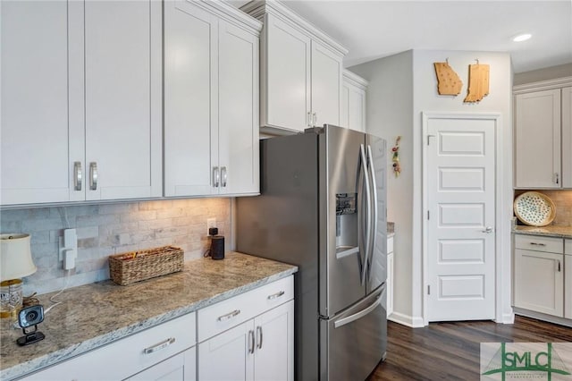 kitchen with white cabinetry, light stone counters, stainless steel fridge, and tasteful backsplash