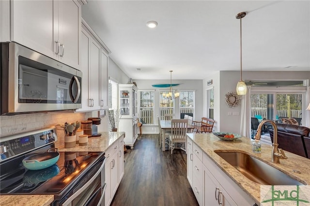 kitchen featuring range with two ovens, light stone countertops, hanging light fixtures, and sink