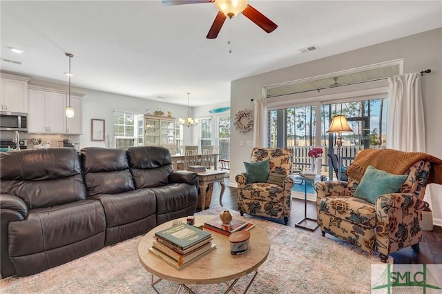 living room with ceiling fan with notable chandelier and light wood-type flooring