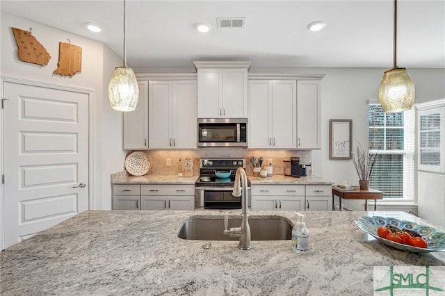 kitchen featuring white cabinetry, sink, stainless steel appliances, and hanging light fixtures