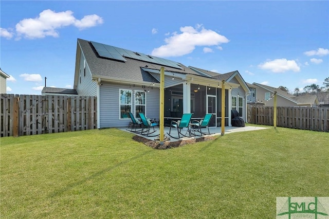 back of house with a yard, a sunroom, a patio, and solar panels