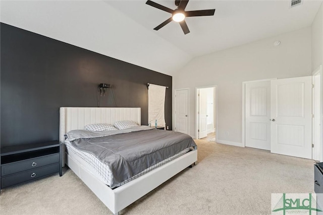 bedroom featuring ceiling fan, light colored carpet, lofted ceiling, and ensuite bathroom