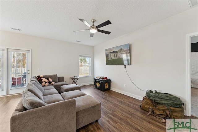 living room with ceiling fan, dark hardwood / wood-style flooring, and a textured ceiling