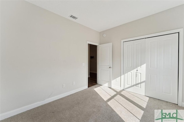 unfurnished bedroom with light colored carpet and a closet