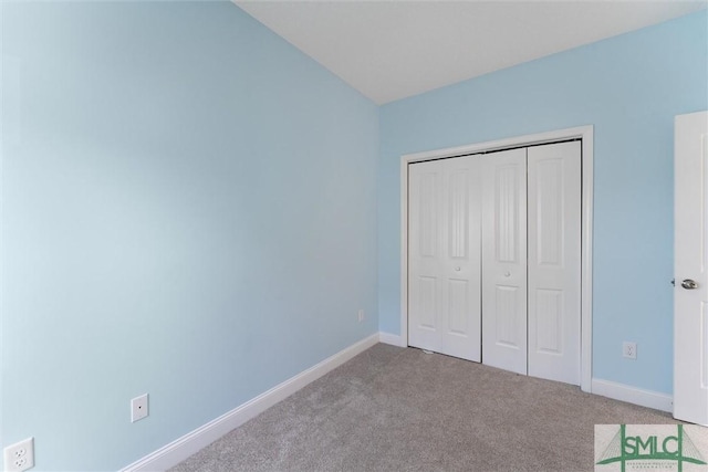 unfurnished bedroom featuring light carpet and a closet