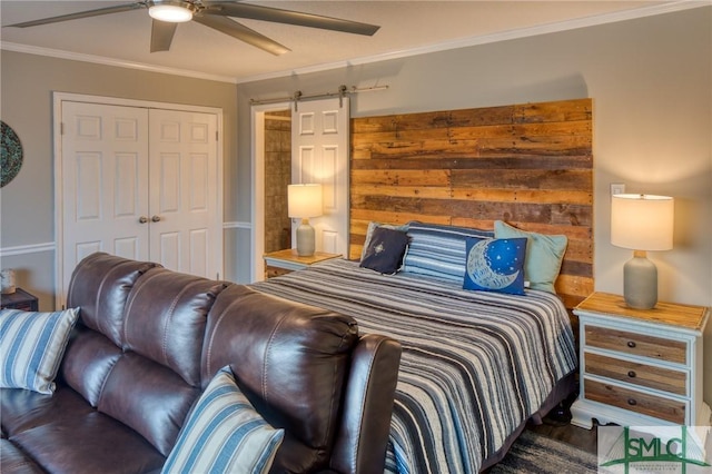 bedroom featuring ceiling fan, ornamental molding, a barn door, and a closet