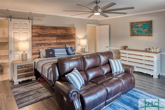 bedroom with crown molding, dark wood-type flooring, a barn door, and ceiling fan