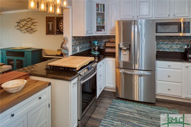 kitchen featuring white cabinetry, ornamental molding, appliances with stainless steel finishes, pendant lighting, and backsplash