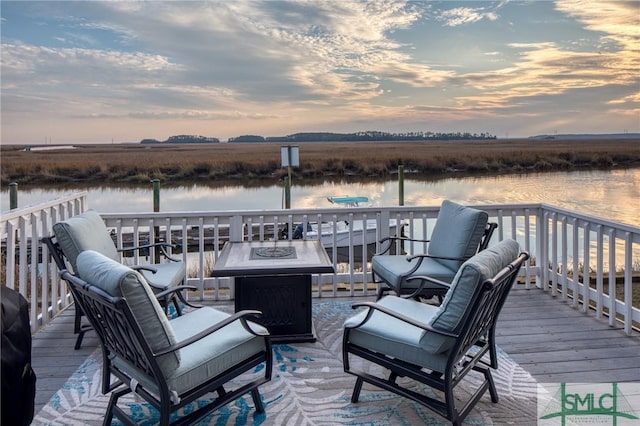 deck at dusk featuring a rural view, a fire pit, and a water view