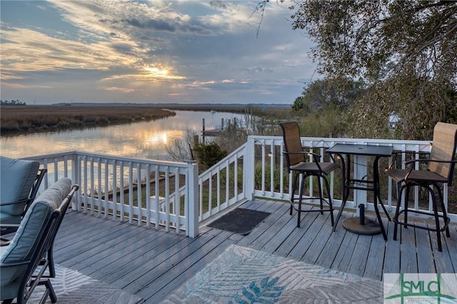 deck at dusk featuring a water view