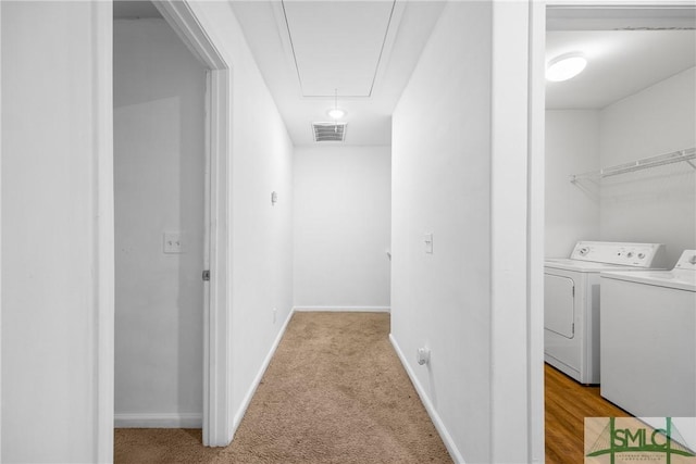 hall featuring independent washer and dryer and light colored carpet