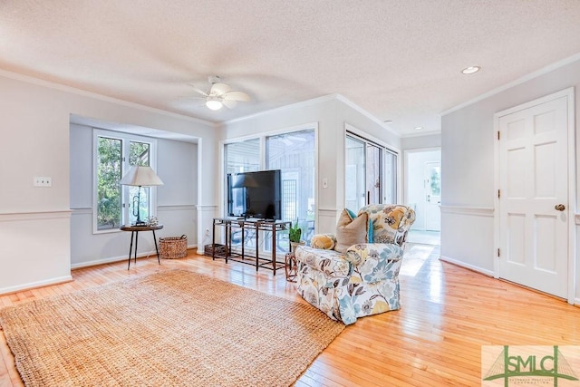 living room featuring ceiling fan, hardwood / wood-style flooring, ornamental molding, and a textured ceiling