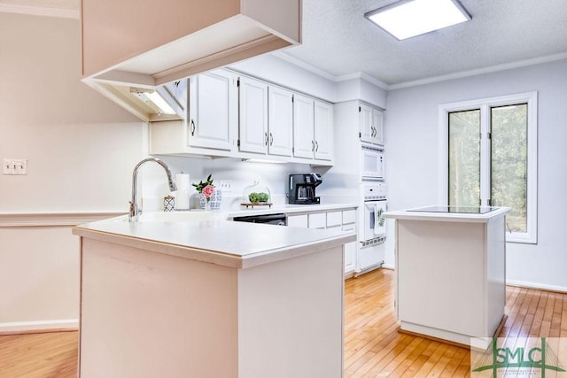 kitchen with a kitchen island, white cabinetry, sink, ornamental molding, and white appliances