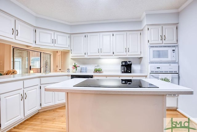 kitchen with white cabinetry, a kitchen island, and white appliances