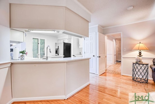 kitchen featuring ornamental molding, kitchen peninsula, stainless steel fridge with ice dispenser, and light wood-type flooring