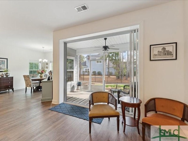 living area with hardwood / wood-style floors and ceiling fan with notable chandelier