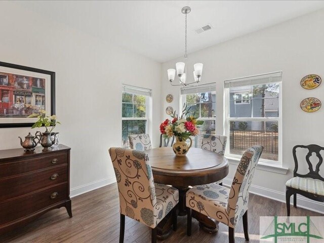 dining area with dark hardwood / wood-style flooring and a notable chandelier