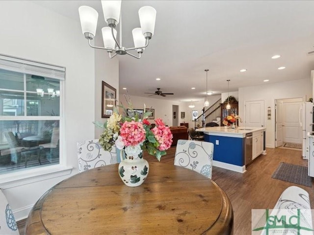 dining room featuring sink, dark wood-type flooring, and ceiling fan with notable chandelier